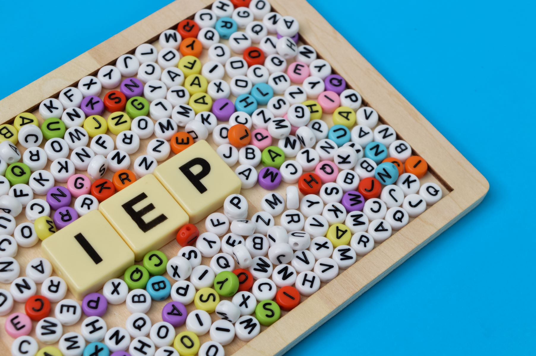 Colorful alphabet beads with three tiles spelling out I E P for individualized education plan.